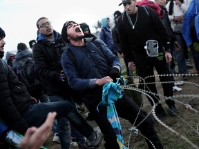 TOPSHOTSMigrants try to remove a fence at the Greek-Macedonian border, near the northern Greek village of Idomeni on November 26, 2015 as migrants and refugees attempt to cross the border. Over 200 migrants on November 26 tried to break through barbed wire fences on Greece's border with Macedonia, throwing stones at riot police. At least three migrants tried to get across in the assault as the crowd shouted