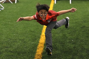 A youngster regains his balance after missing a football thrown at him during the MacDon Fan Experience and Family Zone at the Axworthy Health & Recplex on the University of Winnipeg campus on Thu., Nov. 26, 2015. Kevin King/Winnipeg Sun/Postmedia Network