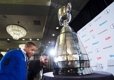 Edmonton Eskimos teammates Sederrik Cunningham, left, and Nate Coehoorn have a close look at the Grey Cup during the team lunch in Winnipeg, Man., on Thursday, November 26, 2015 before the upcoming 103rd CFL Grey Cup game against the Ottawa Redblacks. THE CANADIAN PRESS/Nathan Denette