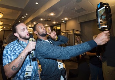 Edmonton Eskimos Kenny Stafford, right, and Aaron Grymes left, poses for a selfie with the Twitter Mirror during the team lunch in Winnipeg, Man., on Thursday, November 26, 2015 before the up coming 103rd CFL Grey Cup game against the Ottawa Redblacks. THE CANADIAN PRESS/Nathan Denette