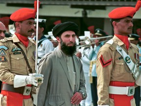 In this Wednesday, June 26, 1996 file photo, Gulbuddin  Hekmatyar, center, passes in front of an honor guard in the Afghan capital of Kabul, Afghanistan. Seeking to gain new leverage, a notorious Afghan warlord who was designated a "global terrorist" by the United States and blacklisted by the United Nations along with Osama bin Laden, wants to come out of the shadows. In videotaped remarks to the AP, Gulbuddin Hekmatyar casts himself as an interlocutor who can help bring about peace but it's hard to gauge what role, if any, the feared mujahedeen leader could play in Afghan politics.  (AP Photo, File)