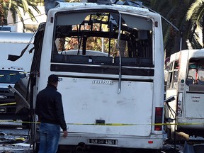 A plainclothes police officer walks beside the bus that exploded Tuesday in Tunis, Wednesday Nov. 25, 2015.  (AP Photo)