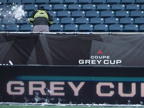 A workers clears the snow from the stands at the Investors Group Field in Winnipeg on Wednesday, Nov.25, 2015. The Grey Cup is now sold out. (THE CANADIAN PRESS/Nathan Denette)