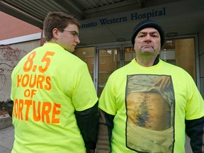 Bruce Smith and his son Graham were protesting in front of Toronto Western Hospital Friday. Smith says the hospital took too long to call him when his wife's back surgery went bad six years ago. He says she repeatedly asked staff to call him during the ordeal, which required her abdomen to get cut open. (Michael Peake/Toronto Sun/Postmedia Network)
