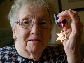 Victoria Stirling holds the Arctic Cross awarded to her late husband, Harvey, seen at right, after her hard work dealing with several governments. (MIKE HENSEN, The London Free Press)