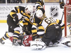 Kingston Frontenacs defencemen Chad Duchesne, left, and Roland McKeown pile on Guelph forward Givani Smith in front of goaltender Jeremy Helvig during the first period Friday night at the Rogers K-Rock Centre. (Elliot Ferguson/The Whig-Standard)