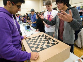 Hamilton high schoolers Samuel Cymbaluk and Colin Daly discuss Chess Mate, an automated board that provides realistic chess piece movements using hidden motors and magnets, with judge and Western University engineering student Anoop Toor, left, at the Hack Western showcase at Western?s Althouse College Sunday. (CRAIG GLOVER, The London Free Press)