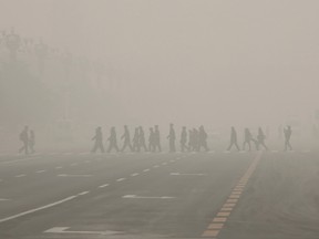 Pedestrians and police cross the street at a crosswalk at the Tiananmen Square during a heavily polluted day in Beijing, China, on Nov. 30, 2015. (REUTERS/Kim Kyung-Hoon)