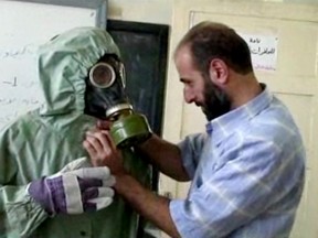 This image made from an AP video posted on Sept. 18, 2013, shows a volunteer adjusting a students gas mask and protective suit during a session on reacting to a chemical weapons attack, in Aleppo, Syria. (AP Photo via AP video, File)