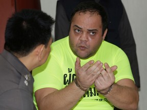 French drug trafficker Andre Cabau, right, talks with a Thai police officer during a press conference in Bangkok, Thailand, on Nov. 30, 2015. Cabau, 39, who was part of a notorious international network that authorities say copied tactics from Hollywood's "Fast and Furious" films, was arrested in Bangkok Friday for having entered Thailand with a fake French passport. Cabau will be deported to continue serving a sentence in France on drug trafficking charges, said Thai and French police. (AP Photo/Sakchai Lalit)