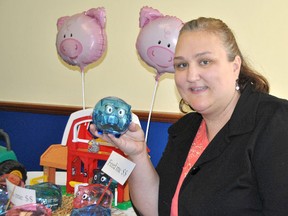 Local Canadian Cancer fundraising coordinator, Laura Pethick, holds one of the piggy banks up for adoption on Dec. 4 to support the Wheels of Hope transportation program. (Laura Cudworth/Postmedia Network)