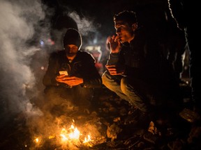 A group of men try to warm up next to a bonfire on a beach shortly after their arrival in a dinghy, with other refugees and migrants, from the Turkish coast to the northeastern Greek island of Lesbos, on Monday, Nov. 30, 2015.  The International Organization for Migration said almost 900,000 people fleeing conflict and poverty in the Middle East, Africa and Asia have entered Europe this year seeking sanctuary or jobs. More than 600,000 have entered through Greece, many after making the short sea crossing from Turkey. (AP Photo/Santi Palacios)