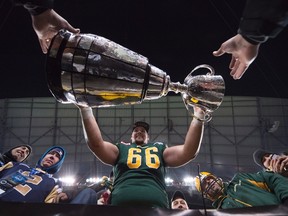 Edmonton Eskimos offensive lineman Matt O'Donnell, a graduate of Holy Cross Catholic Secondary School and Queen’s University, takes the Grey Cup into the stands with the fans following his team’s 26-20 win over the Ottawa Redblacks in Winnipeg on Sunday. (Nathan Denette/The Canadian Press)