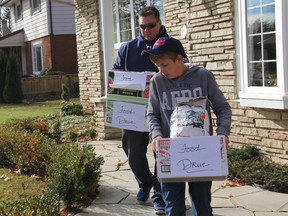 Welland firefighter Derek David and his son Chayse collect a big donation on Donna Marie Drive while volunteering for the Welland Community Food Drive on Saturday, November 7, 2015 in Welland, Ont. Greg Furminger/Welland Tribune/Postmedia Network