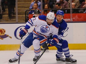 Andrej Sekera battles Maple Leafs forward Michael Grabner for the puck during Monday's game in Toronto. (Dave Thomas, Postmedia Network)