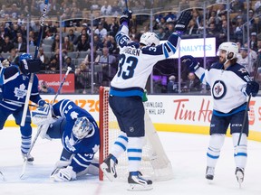 Winnipeg Jets' Dustin Byfuglien, centre, and Mathieu Perreault, right, celebrate Byfuglien's goal in front of Toronto Maple Leafs' goaltender James Reimer during first period NHL hockey action, in Toronto, on Wednesday, Nov. 4, 2015.