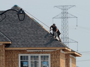 A construction worker shingles the roof of a new home in a development in Ottawa on July 6, 2015. After flirting with another recession earlier this year, Canada's economy rebounded with growth in the third quarter, according to Statistics Canada. THE CANADIAN PRESS/Sean Kilpatrick