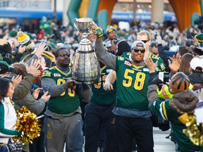 Eskimos' Almondo Sewell (90) and Tony Washington (58) carry the Grey Cup into an Edmonton Eskimos Fan Rally for the Grey Cup champions at Churchill Square in Edmonton, Alta., on Tuesday December 1, 2015. The team beat the Ottawa Redblacks 26-20 in the 103rd Grey Cup in Winnipeg on Sunday, Nov. 29. Ian Kucerak/Edmonton Sun/Postmedia Network