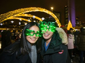 Zhuoyi Wang (left) and her friend Jiacheng Wang get into the spirit of New Year's Eve with themed glasses at Nathan Phillips Square in Toronto December 31, 2014. (Ernest Doroszuk/Toronto Sun)