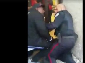 Andrew Burger interferes as a Toronto Police officer tries to make an arrest at an LCBO outlet located inside the Sheridan Mall at Jane St. and Wilson Ave. Nov. 27, 2015. (Framegrab)