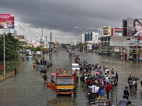 People stand on a flooded road in Chennai, India, December 2, 2015. The heaviest rainfall in over a century caused massive flooding across the Indian state of Tamil Nadu. (REUTERS/Stringer)