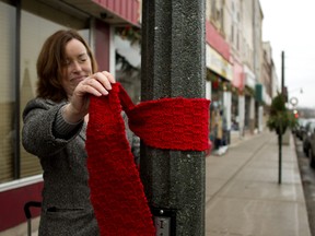 Oxford County public health nurse Gayle Milne ties a red scarf around a street light in Ingersoll as part of the Red Scarf Project to mark World Aids Day on Monday. (BRUCE CHESSELL/Sentinel-Review)