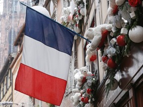 A French flag hangs from a window of a restaurant decorated for Christmas holiday season in Strasbourg, France, November 27, 2015 after the French President called on all French citizens to hang the tricolour national flag from their windows to pay tribute to the victims of the Paris attacks during a national day of homage.  REUTERS/Vincent Kessler