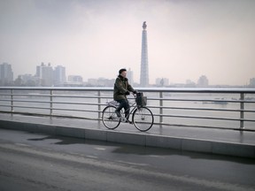A North Korean man cycles over the Taedong river with the Juche Tower seen in the background on Wednesday, Dec. 2, 2015, in Pyongyang, North Korea. (AP Photo/Wong Maye-E)