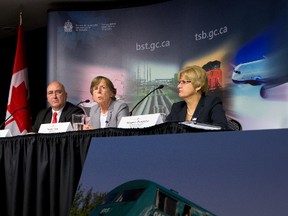 A photograph of the train damaged in the 2013 collision between a Via Rail train and OC Transpo bus is seen as Transportation Safety Board Investigator-in-charge Rob Johnston (left), TSB Chair Kathy Fox and Board Member Helene Gosselin speak to media after releasing the final report in Ottawa on Wednesday December 2, 2015. Errol McGihon/Ottawa Sun/Postmedia Network