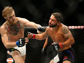 Conor McGregor, left, connects with a left hand to the face of Chad Mendes during their interim featherweight title bout at UFC 189 Saturday, July 11, 2015, in Las Vegas. (AP Photo/John Locher)