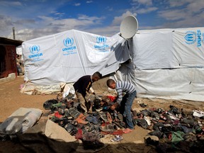 Syrian refugee boys help their family to collect shoes to be added under a fire to boil water outside their family's tent at a refugee camp in the town of Hosh Hareem, in the Bekaa valley, east Lebanon, Wednesday, Oct. 28, 2015. The United Nations said Tuesday the worsening conflict in Syria has left 13.5 million people in need of aid and some form of protection, including more than six million children. (AP Photo/Hassan Ammar)
