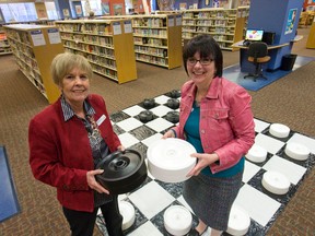 London Public Library director Anne Baker, left, and chief executive Susanna Hubbard Krimmer, right, prepare to play a game of checkers, one of the value-added features offered by the library, in the children's area of the Central Branch on Dundas Street in London on Thursday. Craig Glover/The London Free Press/Postmedia Network