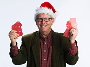 Edmonton Sun columnist Graham Hicks holds up Wal-Mart gift cards for Adopt-A-Teen at the Edmonton Sun studio in Edmonton, Alta., on Friday, Dec. 12, 2014. Hicks started Adopt-A-Teen 15 years ago. Codie McLachlan/Edmonton Sun