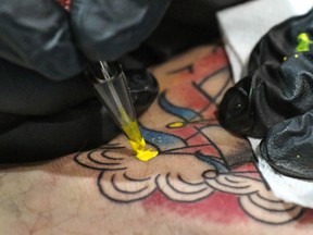 Josh Stow of Club Tattoo works on Richard Kain's leg art at the Calgary Tattoo And Arts Festival at the BMO Centre in Calgary, Ab., on Saturday October 17, 2015. Mike Drew/Calgary Sun