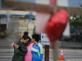 Kayla Gaskill, left, Gaskill's mother and Connie Pegler, right, pay respect at a makeshift memorial for the victims of Wednesday's shooting rampage, Friday, Dec. 4, 2015, in San Bernardino, Calif. Gaskill said her friend Daniel Kaufman was killed in the shooting. (AP Photo/Jae C. Hong)