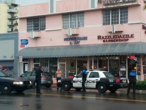 In this photo provided by Marcellus Johnson, authorities draw their guns on a man suspected in a bank robbery, Saturday, Dec. 5, 2015, in Miami Beach, Fla. Police said they killed the man, who they say had a straight edge razor in his hand. (Marcellus Johnson via AP)