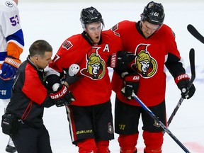 Ottawa Senators center Kyle Turris (7) is assisted off the ice by Mark Stone (61) and head athletic therapist Gerry Townsend after and awkward collision against the New York Islanders during NHL action in Ottawa, Ont. on Saturday December 5, 2015. Errol McGihon/Ottawa Sun/Postmedia Network