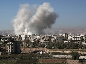 Smoke billows from buildings following a reported air strike in Damascus' rebel-held suburb of Zamalka on December 6, 2015. AFP PHOTO / AMER ALMOHIBANY