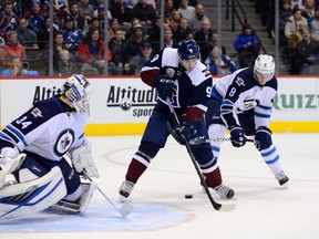 Colorado Avalanche centre Matt Duchene (9) attempts to control the puck as Winnipeg Jets defenseman Jacob Trouba (8) lifts his stick in front of goalie Michael Hutchinson (34) in the second period at the Pepsi Center. (Ron Chenoy-USA TODAY Sports)