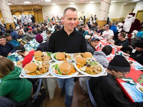 Shawn Leitch carries plates of food during one of the Hope Mission’s Christmas banquets on Monday. A charity meal changed the life of Leitch, who was struggling with addiction and homelessness. Now he works at the agency providing help to those struggling in poverty. (DAVID BLOOM/EDMONTON SUN)