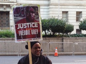 Demonstrator Arthur Johnson carries a sign advocating justice for Freddie Gray on Monday, Dec.  7, 2015, outside the courthouse in Baltimore where the trial of Offcer William Porter enters its second week. (AP Photo/David Dishneau)