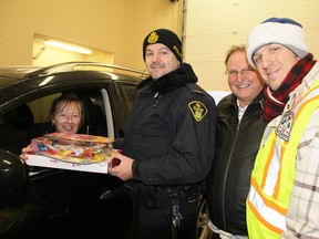 Jennifer Deslippe, of Corunna, is shown in this file photo handing toys to OPP Const. Paul Primeau, left, Operation Christmas Tree's  Fred Strickland, and Shaun Antle, with the Corunna Community Policing Committee, during a previous annual food, toys and cash donations drive-through for the Christmas hamper program in St. Clair Township. This year's drop off is Saturday, 10 a.m. to 2 p.m., at the OPP office on Lyndoch Street in Corunna. (File photo/THE OBSERVER)