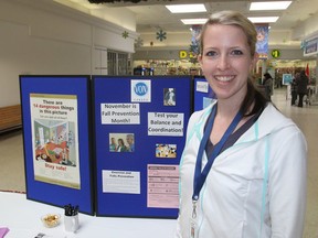 Danielle Anderson, a fitness instructor with the VON, stands in front of a recent display on falls prevention at the Frontenac Mall. (Michael Lea/The Whig-Standard)
