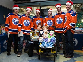 Cohen Samoil, 5, and his mom, Tammy Samoil, get a photo taken with Edmonton Oilers (from left) Andrew Ference, Ryan Nugent-Hopkins, Taylor Hall, Mark Letestu, Teddy Purcell and Matt Hendricks at the Stollery Children's Hospital in Edmonton, Alta., on Tuesday, Dec. 8, 2015. Codie McLachlan/Edmonton Sun