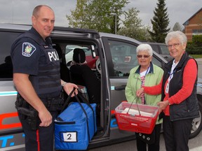 Const. Brian Kempster helps Meals on Wheels volunteers Doreen Brown and Pat Oldham load meals at the Seniors' Centre.