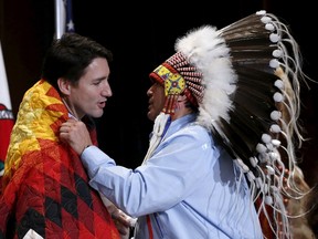 Assembly of First Nations National Chief Perry Bellegarde (R) adjusts a blanket presented to Canada's Prime Minister Justin Trudeau during the Assembly of First Nations Special Chiefs Assembly in Gatineau, Canada, December 8, 2015. REUTERS/Chris Wattie