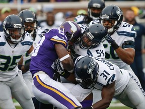 Vikings running back Adrian Peterson (28) is stopped by Seahawks defenders during NFL action in Minneapolis on Dec. 6, 2015. The Cardinals play the battered Vikings on Thursday in Arizona. (Ann Heisenfelt/AP Photo)