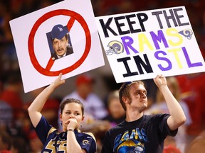 In this May 29, 2015, file photo, fans hold up signs with a picture of St. Louis Rams owner Stan Kroenke and “Keep the Rams in STL” during a baseball game in St. Louis. (AP Photo/Billy Hurst, File)