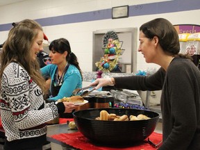 St. Clair Secondary School student Jenah Plaine, 16, gets served up a bun by school counsellor Rebecca Mayo on Thursday December 10, 2015 in Sarnia, Ont. Six hundred students and staff members enjoyed a lunch-time Christmas meal prepared by cafeteria staff and funded through a Ministry of Education healthy eating grant. (Barbara Simpson/Sarnia Observer/Postmedia Network)