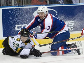 Windsor Spitfires defenceman Liam Murray pushes London Knights forward Cliff Pu into the ice as they chase the puck into a corner during an OHL game in London on Dec. 4. (Craig Glover/Postmedia Network)